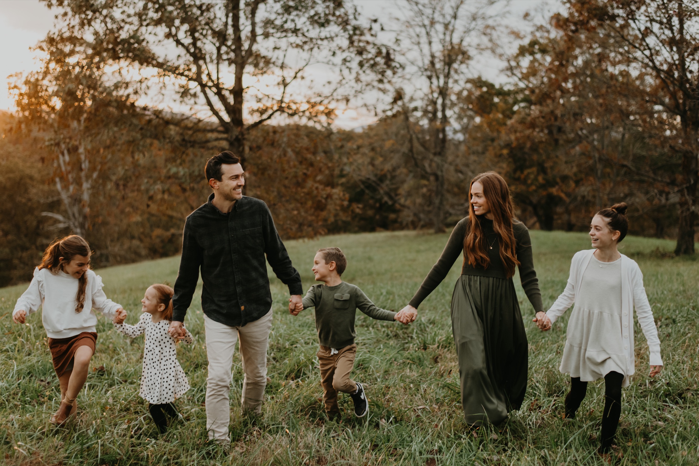 A family running together through an autumn field near Asheville